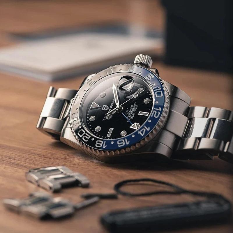 Kelra V3 GMT automatic men’s watch with blue-black bezel displayed beside accessories in flat lay style.